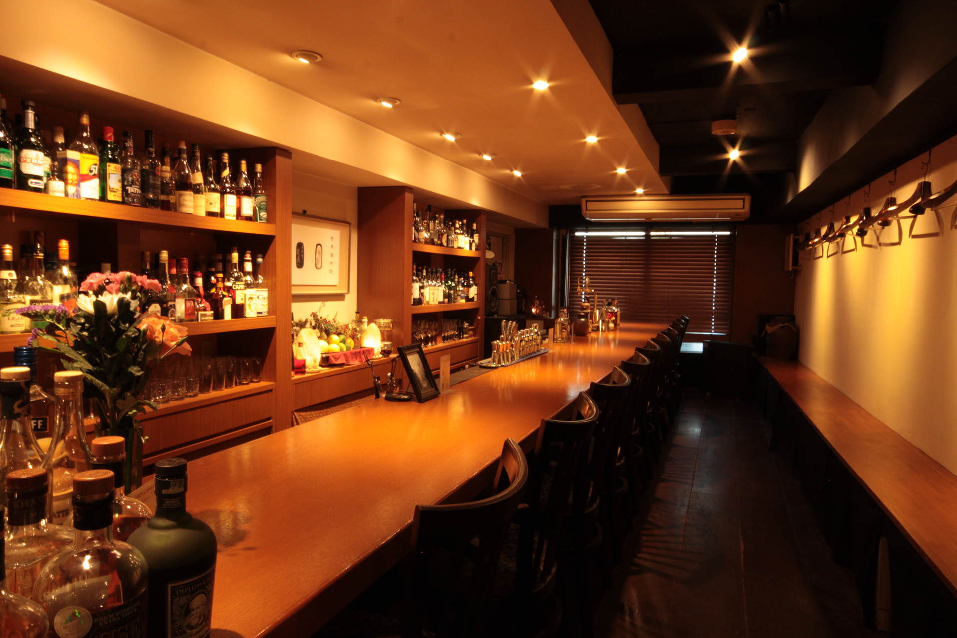 BAR AOTETSUの店内、漆黒のローカウンターとアンバー色に輝くボトル棚